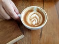 The right hand of a woman holding a cup of hot latte art coffee Royalty Free Stock Photo