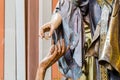 Right hand of wood carved statue of rich woman giving coin to le Royalty Free Stock Photo