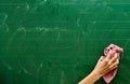 Right hand of a young girl cleaning a green school board with a pink towel Royalty Free Stock Photo