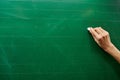 Right hand of a young girl ready to write on the big green school board Royalty Free Stock Photo