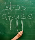 Hand of a young girl writing the words STOP ABUSE on the green school board Royalty Free Stock Photo
