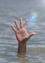 Right man`s hand sticks out from the water in the middle of the ocean