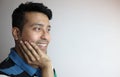 Right side of a cute face of an asian man with hand on chin smiling, feeling glad and looking towards a copy space with white Royalty Free Stock Photo