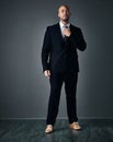 With the right suit, you can do anything. Studio shot of a handsome young businessman adjusting his tie against a gray Royalty Free Stock Photo