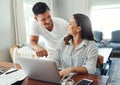 Is that right Thats awesome. a young couple using a laptop to their household budget in the living room at home.