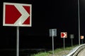 Right turn signs on the night road. Road signs warn of sharp turns in the light of streetlights