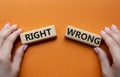 Right or Wrong symbol. Concept word Right or Wrong on wooden blocks. Businessman hand. Beautiful orange background. Business and