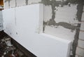 Rigid extruded polystyrene house wall insulation. Insulating house aerated concrete blocks wall with rigid styrofoam outdoors.