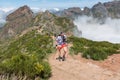 Rigorously equipped athlete finishing the Pico do Areeiro trail race, low clouds and mountains as background, Madeira Island,