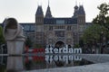 Rijkmuseum building with Giant I am Amsterdam lettering sign refflected on watter in sunny dusk