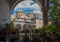 Rila Monastery`s main church framed by arch, plants and flowers