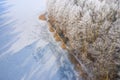 Rime and hoarfrost covering trees. Aerial view of the snow-covered forest and lake from above. Winter scenery. Landscape photo Royalty Free Stock Photo