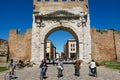 People ride bicycles under Augustus Arch - the ancient romanesque gate and the historical landmark of Rimini, Italy.