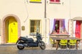 Rimini, Italy, September 19, 2018: table with chairs and motorcycle bike scooter parked on cobblestone street Royalty Free Stock Photo