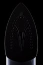 Underside of a clothing iron, rimlit on black Royalty Free Stock Photo