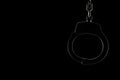 Rimlit locked handcuffs on a black background with copy space