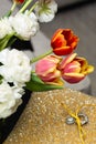 a ring is displayed on a small cushion beside flowers and tulips