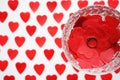 Ring on red hearts in a crystal glass on a white background with hearts Royalty Free Stock Photo