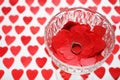 Ring on red hearts in a crystal glass on a white background with hearts Royalty Free Stock Photo