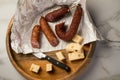 Ring Salami pork sausage with German BierbeiÃÅ¸er and Edamer cheese in wax paper with knife on wooden board background for Brotzeit