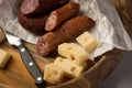 Ring Salami pork sausage with German BierbeiÃÅ¸er and Edamer cheese in wax paper with knife on wooden board background for Brotzeit