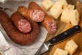 Ring Salami pork sausage with German BierbeiÃÅ¸er and Edamer cheese in wax paper with knife on wooden board background for Brotzeit