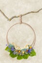 Ring with wildflowers and large green leaves hanging on a branch, a template for photo shoots of newborns