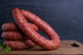 Rings of homemade Krakow sausage on a cutting board, copy-space