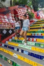 Brazilian girls walk down the colorful steps of the famous Stairway Selaron Escadaria