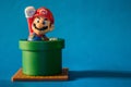 Super Mario with pipe toy figure. There are plastic toy sold as part of the McDonald`s Happy meals. Isolated on blue background.