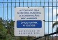 Warning sign in portuguese informing city hall authorization to fenced land with grid