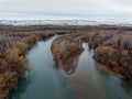 Rio Negro river with snowed cliffs behind aerial view. Alto Valle, Argentina