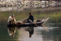 Rio Nilo, near Aswnm, Egypt, February 21, 2017: Two Egyptian fishermen in a small boat fishing, one of them crouched in the stern Royalty Free Stock Photo