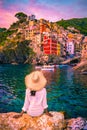 Riomaggiore Cinque Terre Italy , colorful village harbor front by the ocean, young woman watching sunset Royalty Free Stock Photo