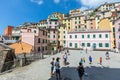 Square with people and children. Colorful houses in the small town of Riomaggiore in Liguria