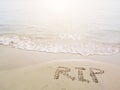 RIP, rest in peace, handwriting on nature sand tropical beach. Words written in sand against the sea in sunny day. Sadness concept Royalty Free Stock Photo