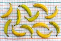 Ripe, appetizing, healthy, large, sweet bananas, neatly lined on checkered tablecloth table on a light background. The