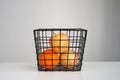 Ripe apples and orange in black grid basket on gray background. Recipe, juice, diet concept.