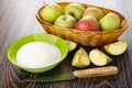 Apples in wicker basket, empty bowl, knife, green bowl with sugar, pieces of apple on table Royalty Free Stock Photo
