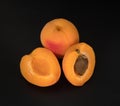 Ripe Apricot fruits, one whole apricot and two divided apricot pieces, on a black background in isolation Royalty Free Stock Photo