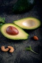 Ripe avocado cut in half with nuts and green leaves on a dark stone background Royalty Free Stock Photo