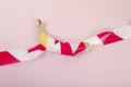 a ripe banana, wrapped in a red and white plastic ribbon