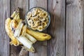 Ripe bananas with peeled peel and banana chips in a bowl on a natural wooden background. Copy space Royalty Free Stock Photo