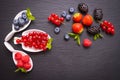 Ripe berry- currants, raspberries and blueberries, lie in a white bowl, mint leaves and side view of strawberries and blackberries Royalty Free Stock Photo