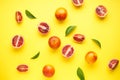 Ripe blood oranges sliced and whole with sprigs of green leaves on a yellow background. Top view Royalty Free Stock Photo