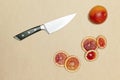 Ripe blood sicilian orange running away from knife cutting it.beige background.Concept of citrus fruits season and
