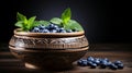 Ripe blueberries and fresh spearmint in clay bowl, rustically staged on wooden table