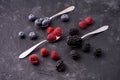 Ripe blueberries, raspberries, blackberries, Mixed berries with three spoons. Various fresh summer berries on dark solid backgroun