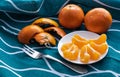 Ripe bright orange tangerines and peeled tangerine wedges in a small white plate. Royalty Free Stock Photo