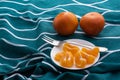 Ripe bright orange tangerines and peeled tangerine wedges in a small white plate. Royalty Free Stock Photo